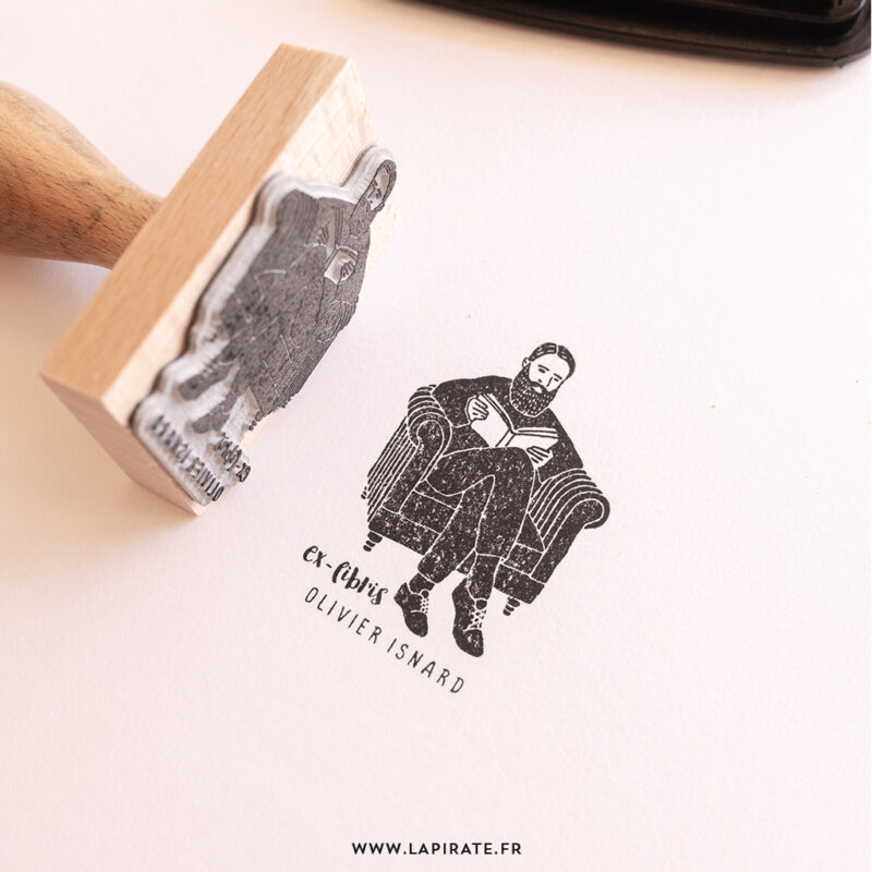 Tampon ex libris illustré d'un homme barbu lisant un livre dans un fauteuil à personnaliser de votre nom pour marquer vos livres - Idée cadeau - La Pirate